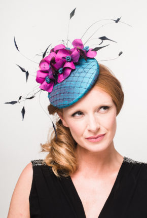 teal silk button with navy veiling overlay, decorated with magenta sewn flowers , scattered veiling and navy coque feathers